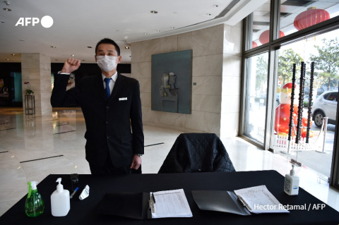 Wuhan hotel security guard checks visitor's temperature - Hector Retamal - AFP